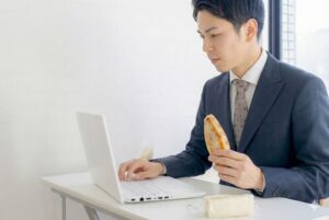 オフィスで間食を摂るビジネスマンのイメージ